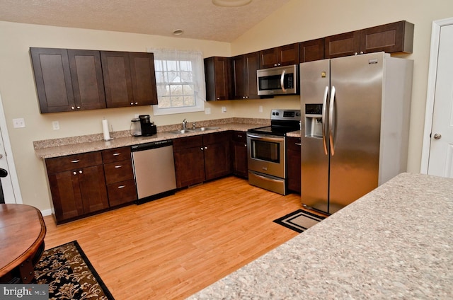 kitchen featuring lofted ceiling, stainless steel appliances, light hardwood / wood-style floors, and dark brown cabinetry