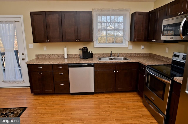 kitchen with dark brown cabinetry, stainless steel appliances, light hardwood / wood-style floors, and sink