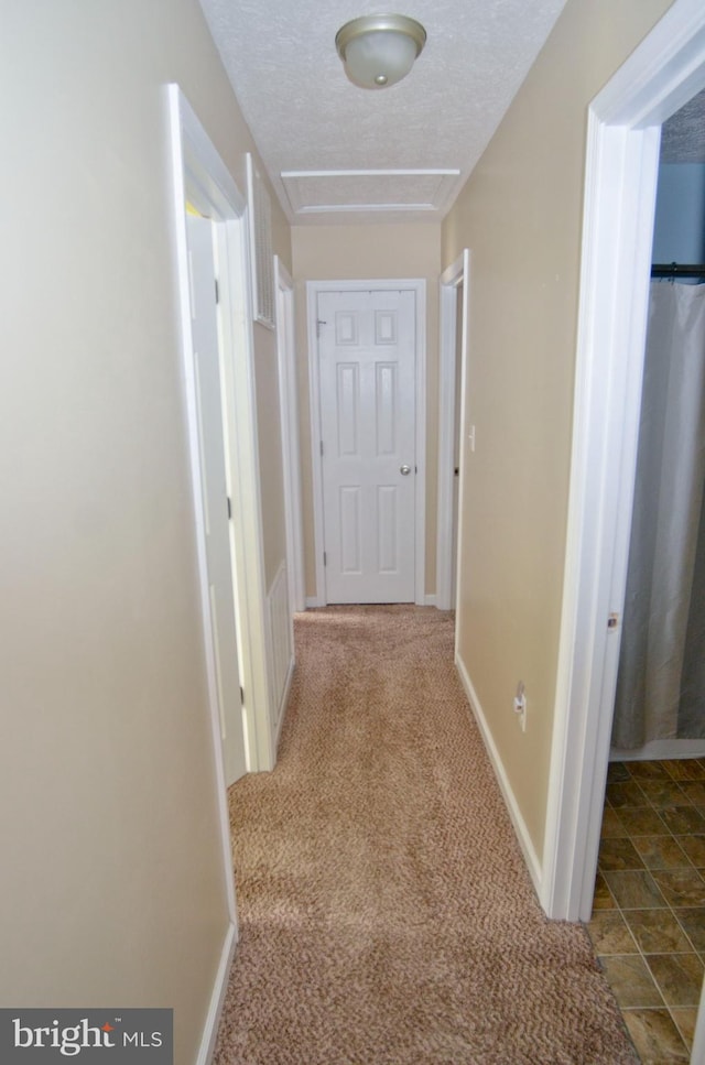 hall with light carpet and a textured ceiling