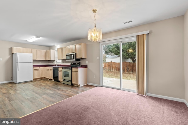 kitchen with pendant lighting, sink, stainless steel appliances, a notable chandelier, and light carpet