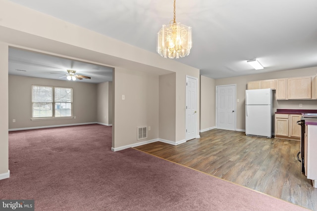 kitchen with ceiling fan with notable chandelier, carpet flooring, hanging light fixtures, and white fridge