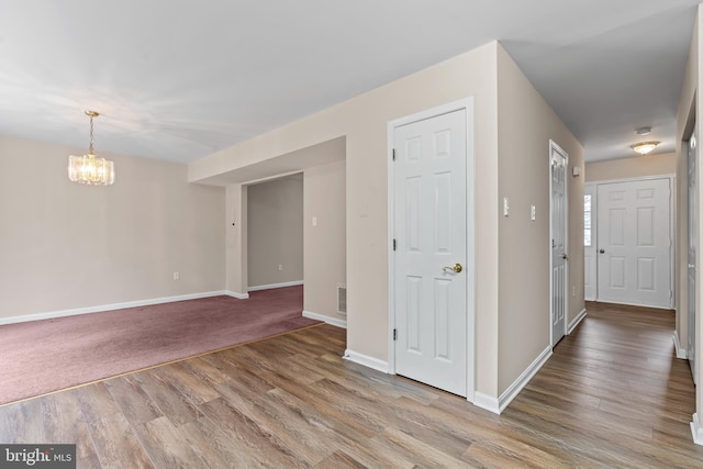 unfurnished room featuring a chandelier and light wood-type flooring