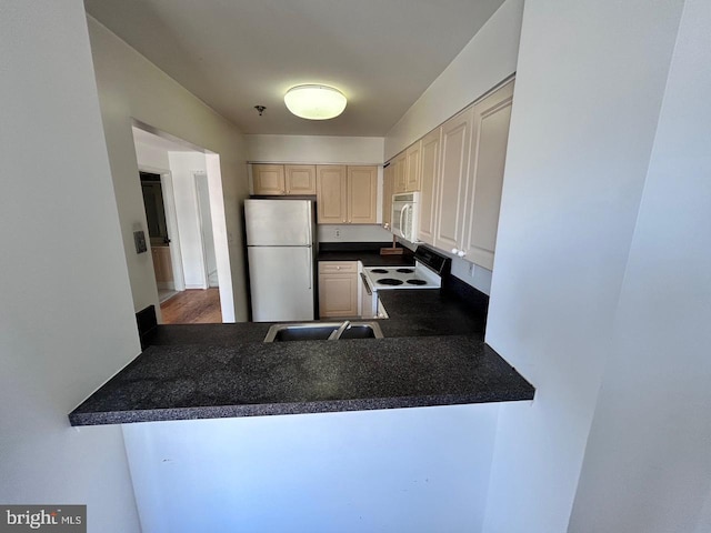 kitchen with sink, white appliances, and kitchen peninsula