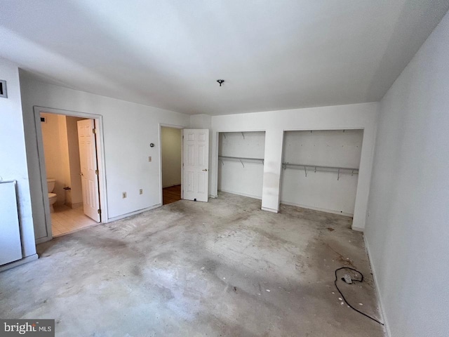 unfurnished bedroom featuring ensuite bathroom and two closets