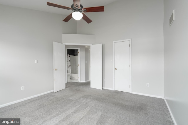 unfurnished bedroom with a high ceiling, light carpet, and ceiling fan