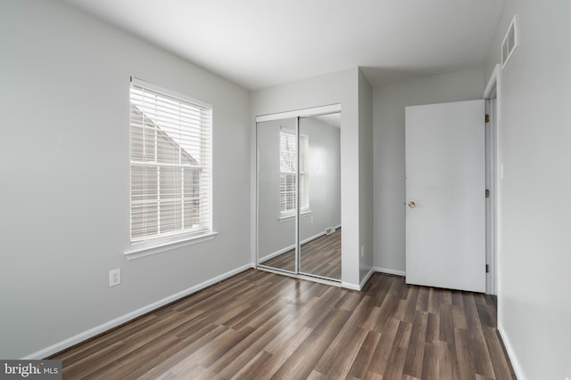 unfurnished bedroom featuring dark wood-type flooring and a closet