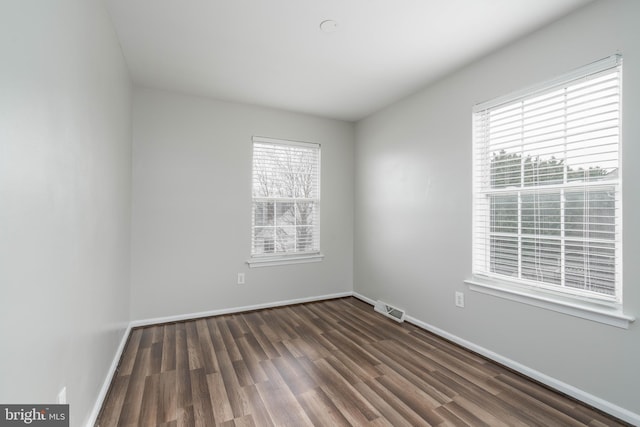 empty room with dark hardwood / wood-style flooring and a wealth of natural light