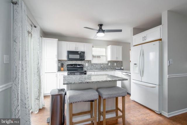 kitchen with a center island, white cabinets, light hardwood / wood-style floors, and black appliances