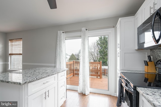 kitchen with white cabinetry, light stone countertops, and black appliances