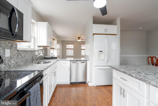 kitchen with backsplash, white cabinets, light wood-type flooring, and black appliances