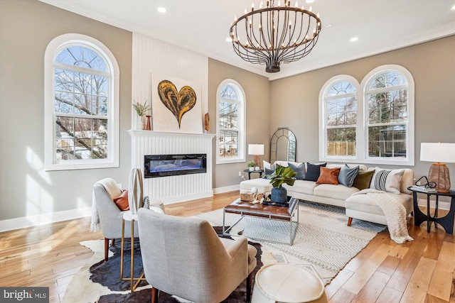 living room with an inviting chandelier, light hardwood / wood-style flooring, and ornamental molding