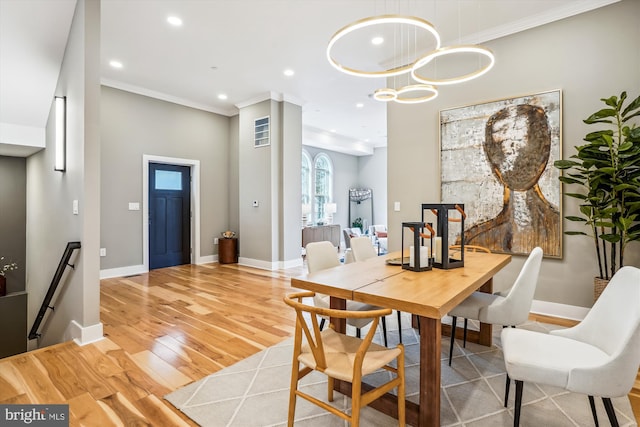 dining space with crown molding and light hardwood / wood-style floors