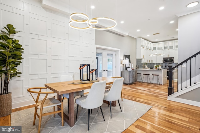 dining space with french doors, an inviting chandelier, and light wood-type flooring