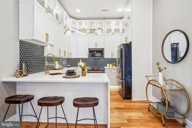 kitchen with sink, high end fridge, white cabinets, built in microwave, and kitchen peninsula