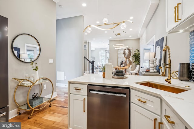 kitchen with pendant lighting, dishwasher, sink, and white cabinets