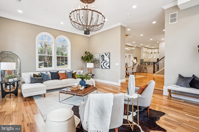 living room with an inviting chandelier, crown molding, and light hardwood / wood-style floors