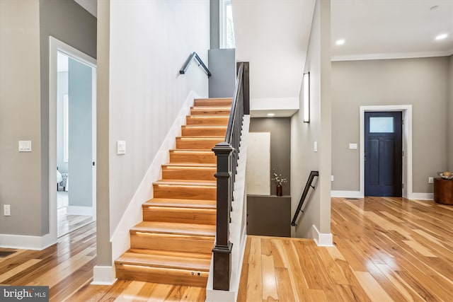 stairs with crown molding and hardwood / wood-style floors