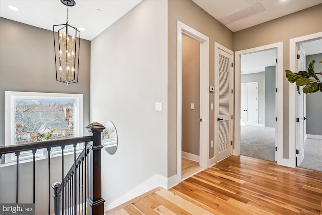 corridor featuring light hardwood / wood-style flooring and a notable chandelier