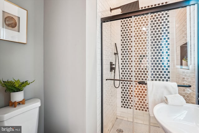 bathroom with sink, a shower with shower door, and toilet