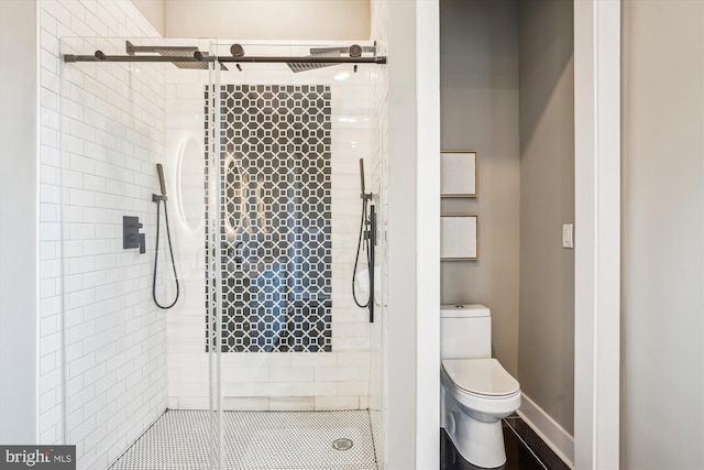 bathroom featuring toilet and a shower with shower door