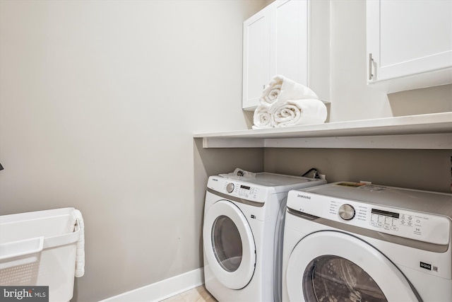 washroom with cabinets and washing machine and clothes dryer