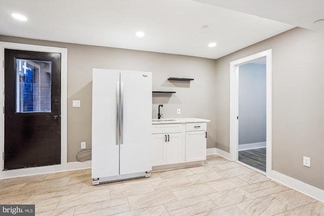 interior space featuring white cabinetry, sink, and white fridge