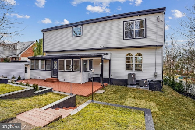 back of property with a sunroom, a yard, central AC, and a deck