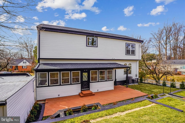 rear view of property featuring central AC unit, a deck, and a lawn