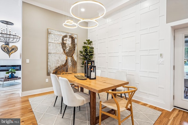 dining space featuring a towering ceiling, ornamental molding, a chandelier, and light wood-type flooring