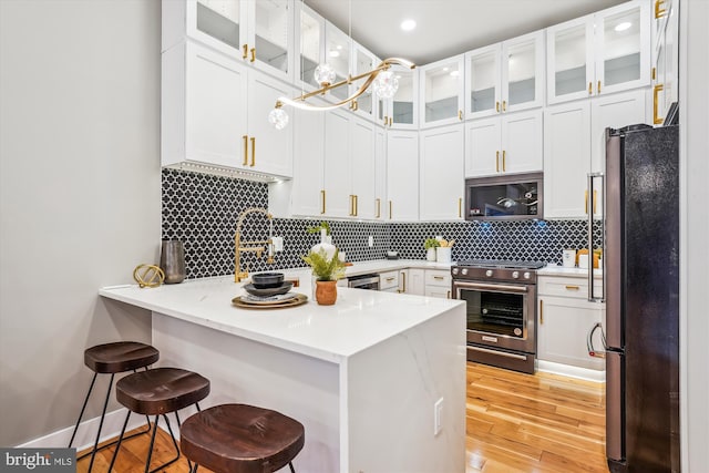 kitchen featuring stainless steel appliances, kitchen peninsula, white cabinets, and a breakfast bar