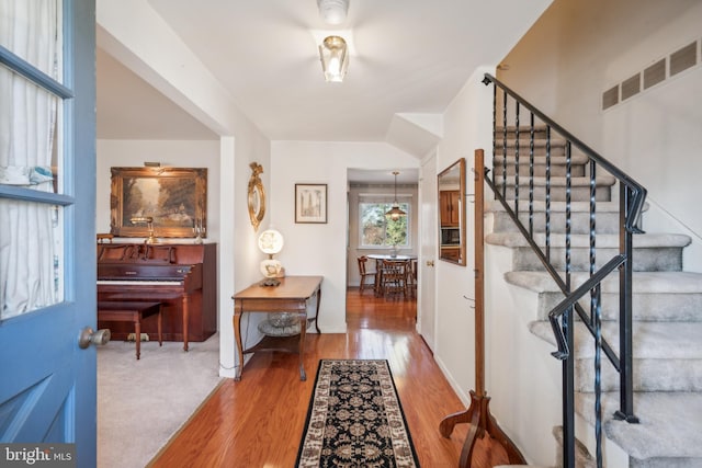 entrance foyer with stairs, visible vents, and wood finished floors