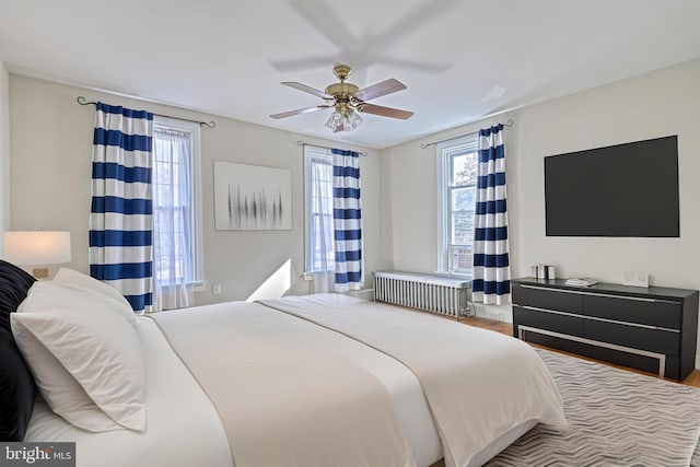 bedroom featuring hardwood / wood-style floors, radiator heating unit, and ceiling fan