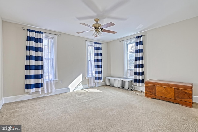 carpeted empty room featuring ceiling fan and radiator