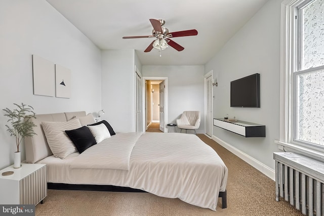 bedroom featuring multiple windows, carpet flooring, radiator heating unit, and ceiling fan