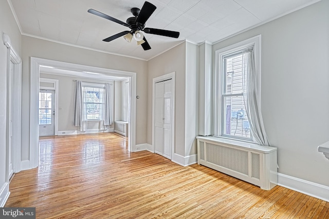 empty room with ceiling fan, ornamental molding, radiator, and light hardwood / wood-style floors