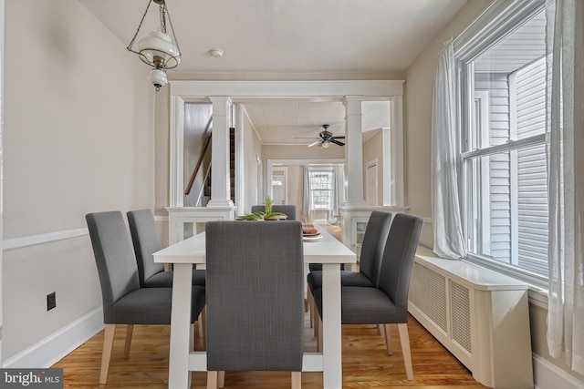 dining room with ornate columns, wood-type flooring, and ceiling fan