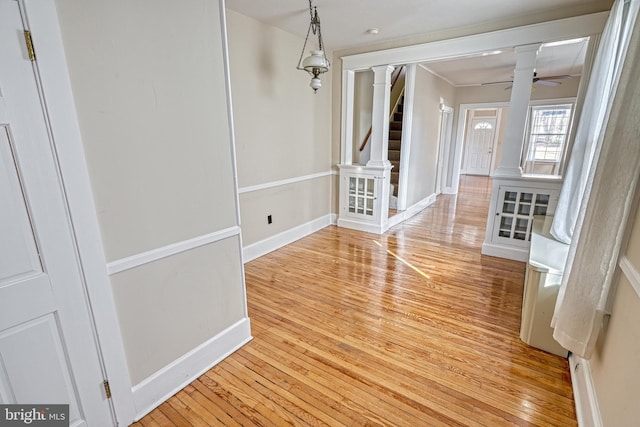 interior space with decorative columns, ceiling fan, and light wood-type flooring