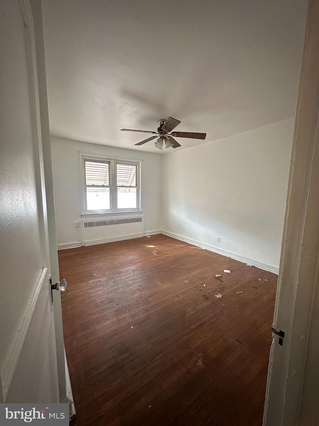 unfurnished room with ceiling fan, radiator heating unit, and dark hardwood / wood-style floors