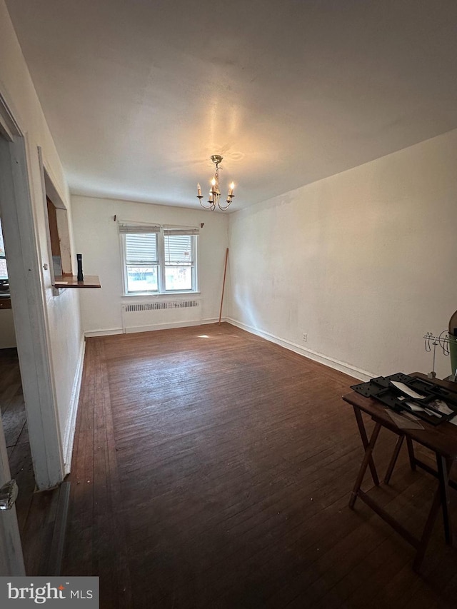 unfurnished living room with radiator, dark wood-type flooring, and a chandelier