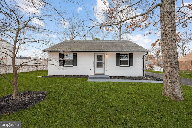 bungalow-style home with a front lawn, brick siding, and a shingled roof