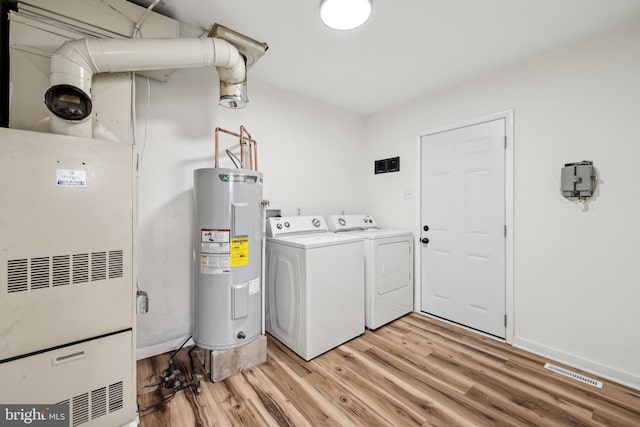laundry area featuring washing machine and clothes dryer, electric water heater, light wood-type flooring, laundry area, and visible vents