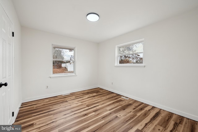 empty room featuring plenty of natural light, baseboards, and wood finished floors