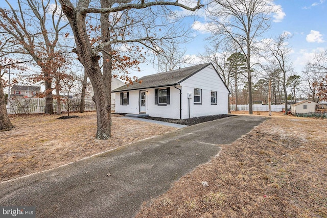 view of front of property with fence, aphalt driveway, brick siding, and roof with shingles