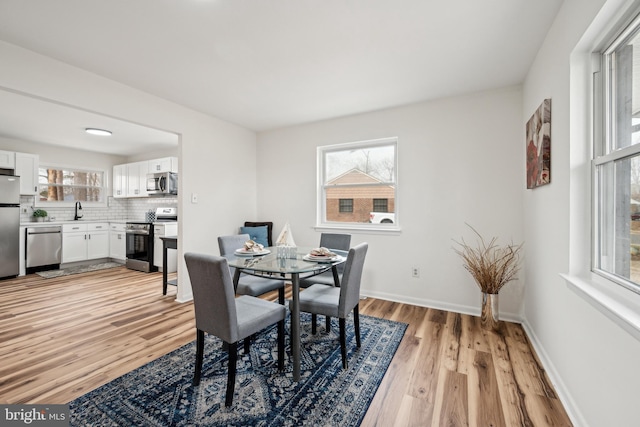 dining space featuring plenty of natural light, light wood finished floors, and baseboards