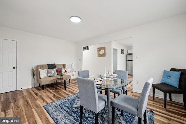 dining room with baseboards, light wood-style floors, and visible vents
