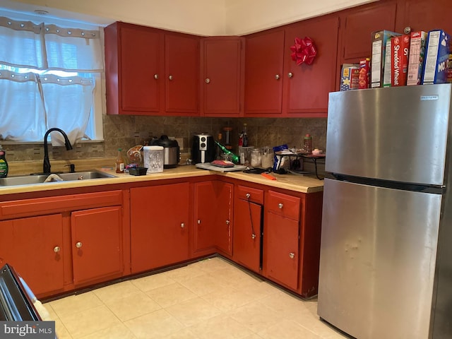 kitchen featuring sink, decorative backsplash, stainless steel fridge, and range