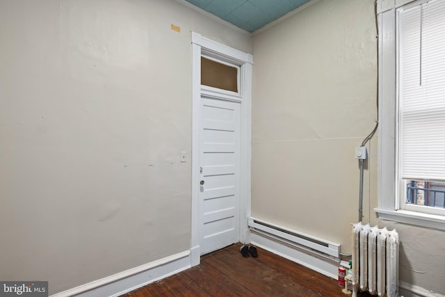 empty room featuring radiator heating unit, dark hardwood / wood-style floors, and a baseboard radiator