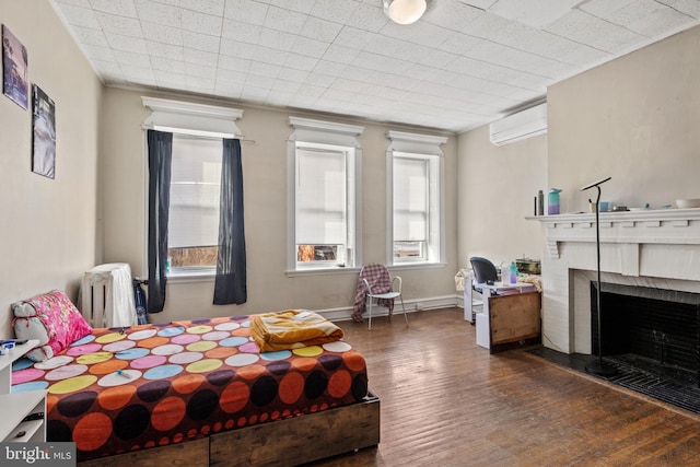 bedroom featuring a wall unit AC, dark hardwood / wood-style floors, and a brick fireplace