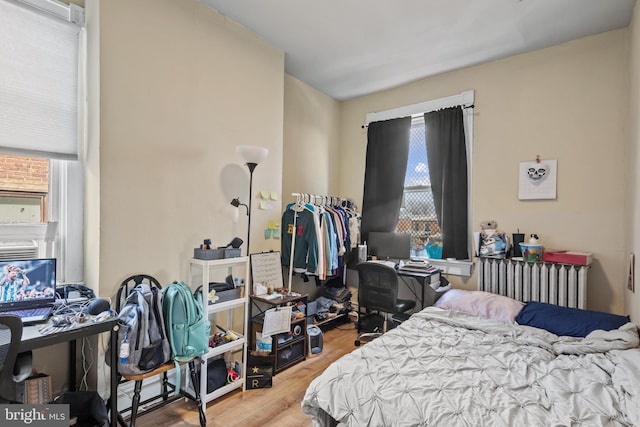 bedroom featuring radiator and hardwood / wood-style flooring