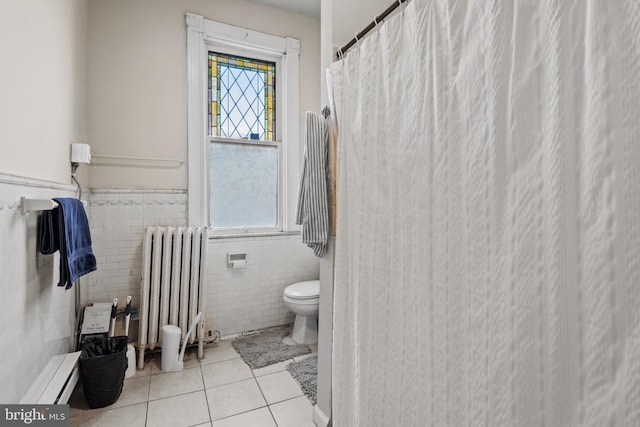 bathroom with tile patterned flooring, radiator heating unit, tile walls, and toilet